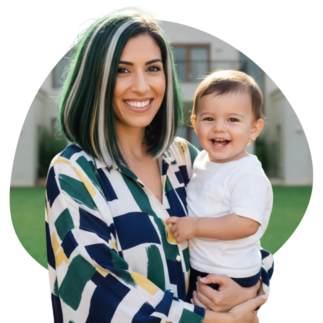 Mother holding her baby and smiling in front of their family home